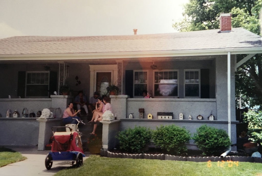 Bill's first home with several people sitting on the front porch.